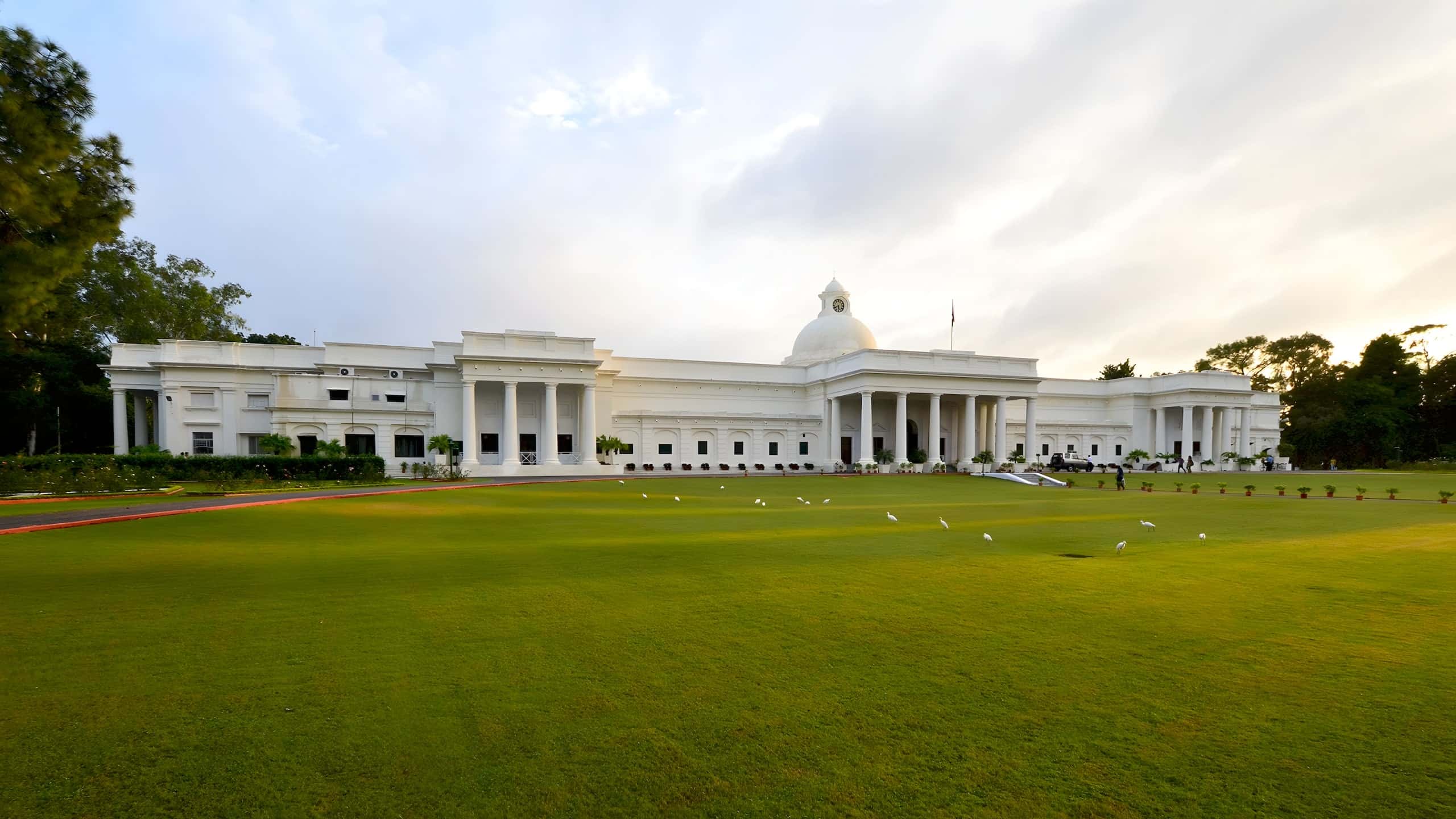 The Main Building of IIT Roorkee, white with a central dome, across a wide green lawn.