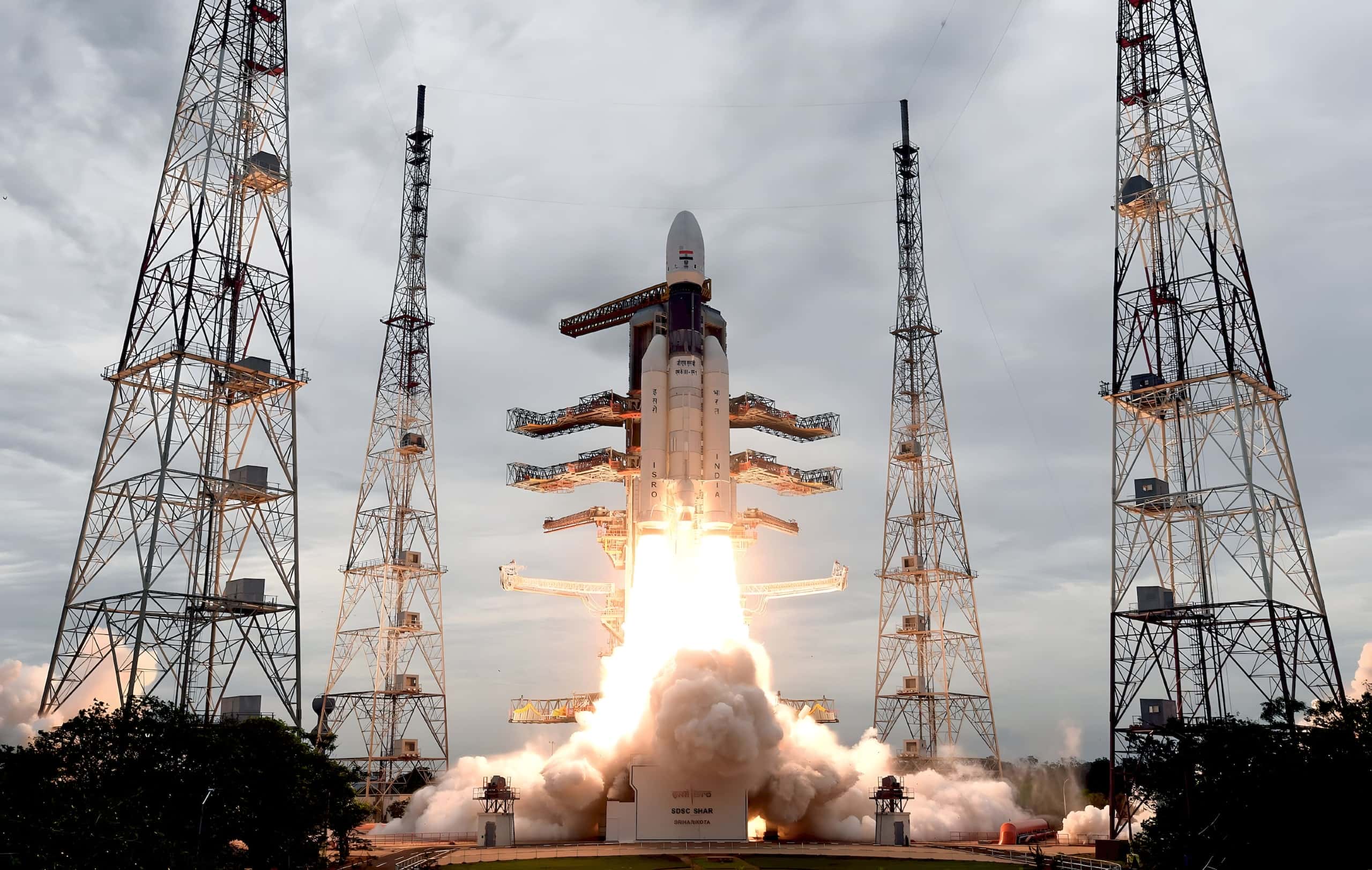 A GSLV rocket lifting off between launch towers.