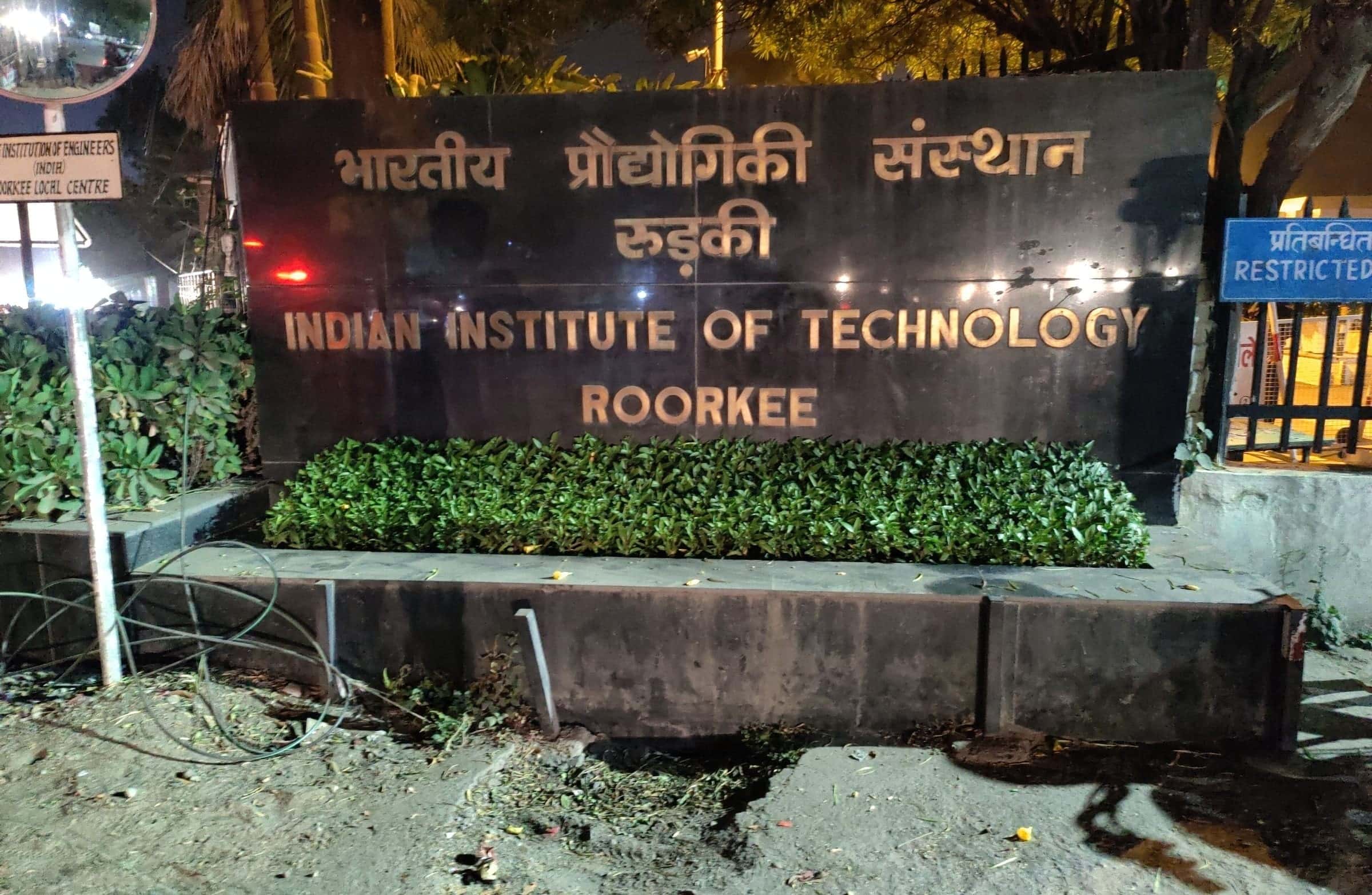 IIT Roorkee name board in Hindi and English, lit at night.