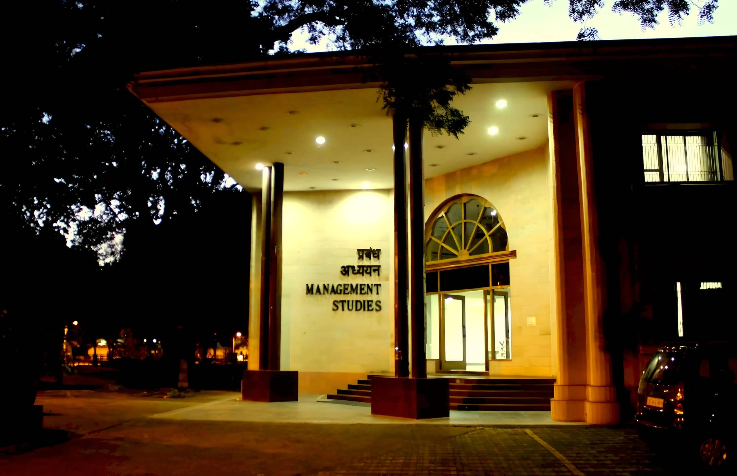 Entrance of the Department of Management Studies building, lit at night.