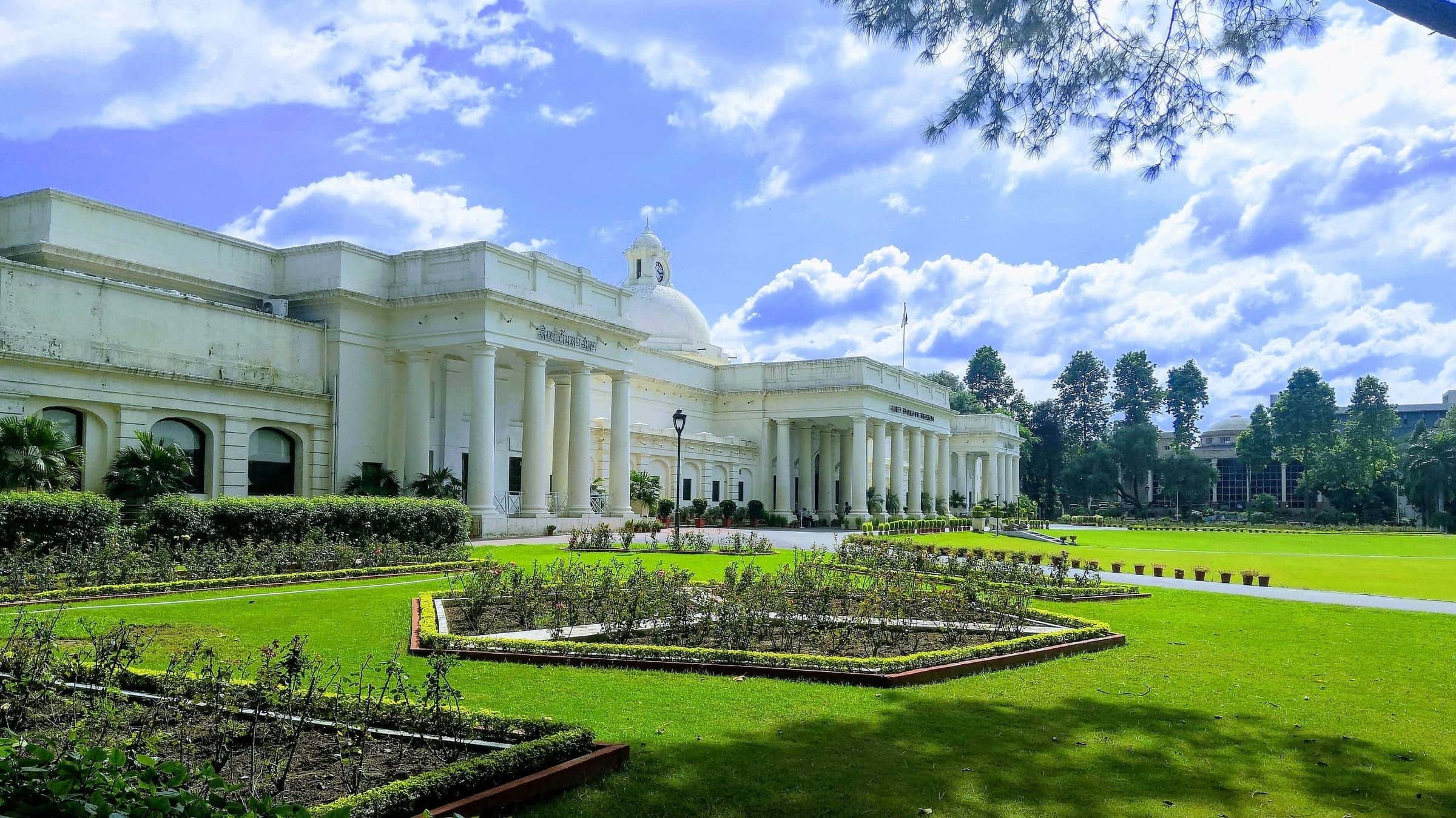 The Main Building under a blue sky, with gardens in front.